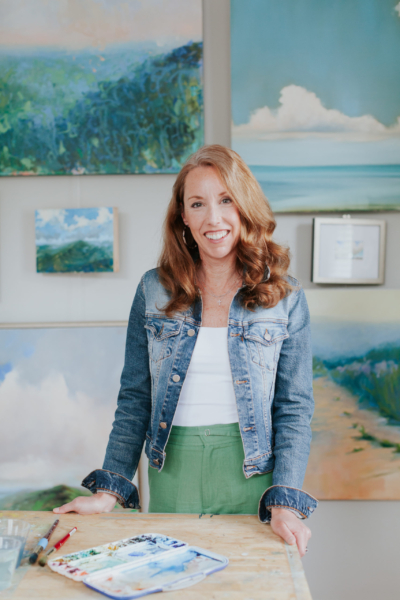Headshot of artist Ashely Sellner with her art in her studio at StudioWorks